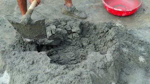 Indian professional construction worker mixes wet grey cement. 4k video clip