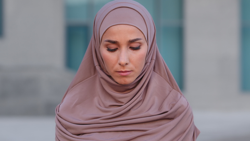 Portrait young beautiful serious Indian girl in pink hijab traditional headscarf lonely muslim woman alone islamic female sad upset arabian lady tourist looking at camera standing outdoors in city | Shutterstock HD Video #1079033741
