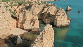Panoramic view of rock formations of Ponta de Piedade, Portugal, Lagos, Europe. Drone flying over two men in boats kayaking between stone mountains at Atlantic ocean. Natural background, 4k footage