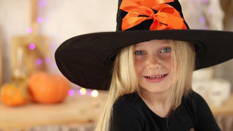 cute little girl blonde in a witch costume on Halloween smiles looking into the camera. high quality video footage. High quality 4k footage
