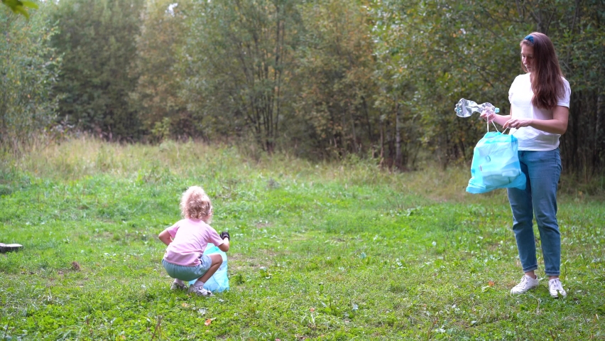 a family of volunteers removes garbage in nature. mother and children, daughter and son clean up garbage, waste bottles in the forest, put them in plastic bags