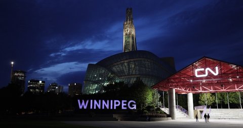 Winnipeg, MB, Canada - Sept 2021: The "Winnipeg" sign with the Canadian Museum of Human Rights in the background as seen in the evening