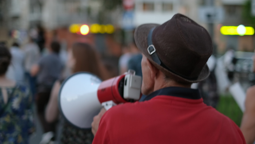 Strike activist demonstrator man on opposition rally riot with megaphone walks. Political protester bullhorn marches in protest crowd. Stop. Male rebel speaking demonstration revolt resistance move. Royalty-Free Stock Footage #1079041211