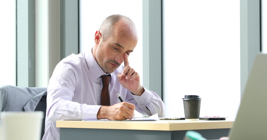 Business man holding laptop computer notebook and smiling at modern office with team.