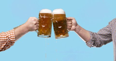 Celebration beer cheers concept - close up male hands holding glasses of beer at Oktoberfest traditional party or victory competition or successful task meeting. Isolated on color background