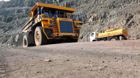 Yellow dump truck in a coal mine. The dump truck drives through the quarry. Large dump truck in a coal mine