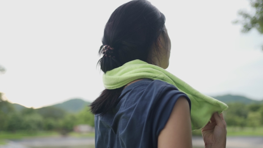 Young asian woman using towel on neck wiping sweat on face and neck during exercise at green park, take a break from training, woman drying sweat, tiredness and sport concept, active healthy lifestyle Royalty-Free Stock Footage #1079063432