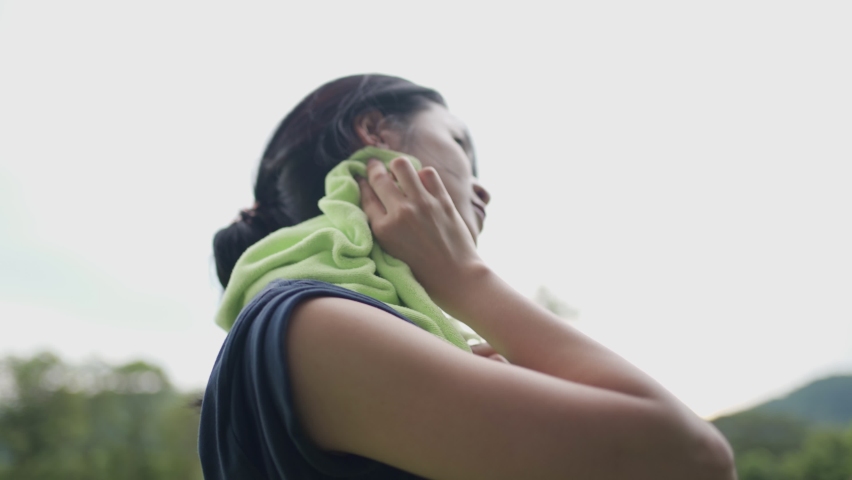 Young asian woman using towel on neck wiping sweat on face and neck during exercise at green park, take a break from training, woman drying sweat, tiredness and sport concept, active healthy lifestyle Royalty-Free Stock Footage #1079063432