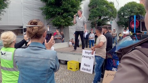 Gifhorn, Germany, September 11, 2021: Teacher of a high school speaks on the stage of a rally against compulsory wearing of masks in the classroom