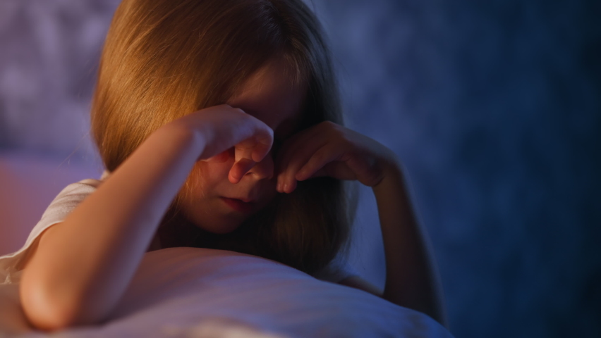 Stressed child wipes away tears and closes face in bedroom Royalty-Free Stock Footage #1079069402