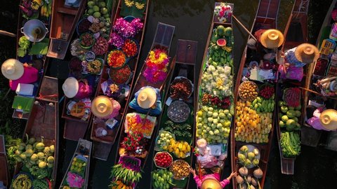 top view from drone of famous and unique floating market at Damnoen Saduak. Plenty of fresh fruits, vegetables, flowers and street food available to buy. 