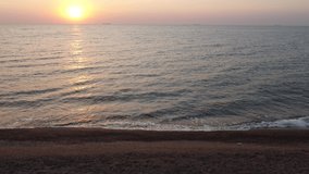 Sunrise and waves on the sea, view from the sandy beach