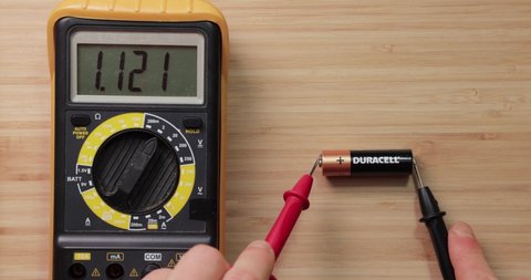 Budapest, Hungary - Circa 2021: Testing AA battery cell from Duracell with digital multimeter tool, voltage check showing low value, battery is used and discharged