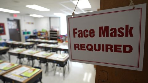 Face Mask Required sign in empty school classroom during pandemic.