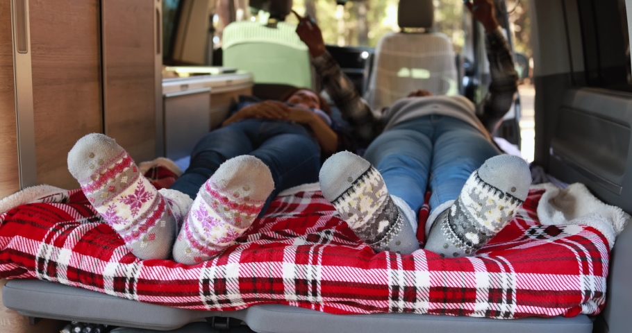 Multiracial senior women realx inside mini van camper wearing cozy socks 