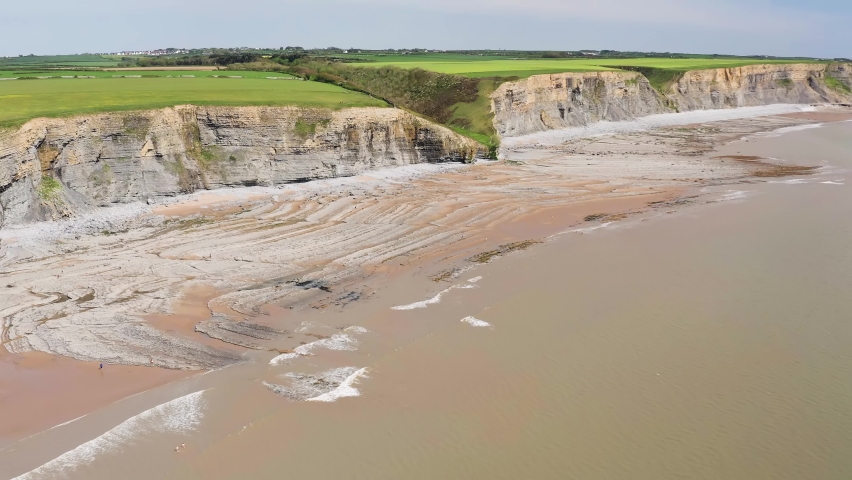 Aerial view flying along a coastline with dramatic limestone cliffs (Southerndown, Wales, UK)