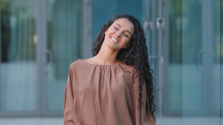 Beautiful happy cheerful young hispanic woman brunette with curly hairstyle caucasian attractive girl model dancing in city on street moving head with long hair enjoy weekend rejoicing dance active | Shutterstock HD Video #1079088458