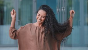 Beautiful happy cheerful young hispanic woman brunette with curly hairstyle caucasian attractive girl model dancing in city on street moving head with long hair enjoy weekend rejoicing dance active - Powered by Shutterstock - Get 15% off with code: PIKWIZARD15