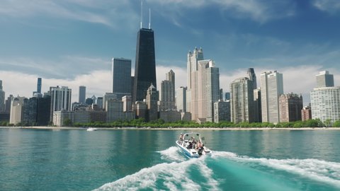 Chicago, Michigan lake, May 2021. Water sports tourism, leisure activity, summer vacation 4K. Aerial view of Chicago skyline and white sailing boat in blue green still waters with downtown background