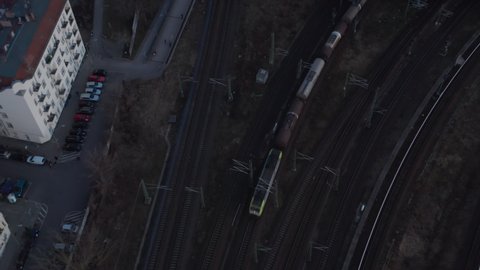 Birds eye view of a passenger train passing by from city and trees in Berlin, Germany surrounded by residential house during an early morning