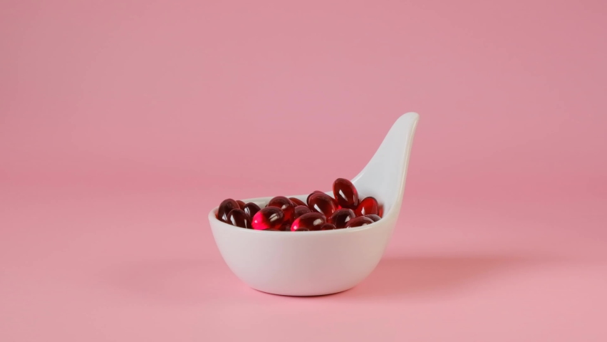 Krill oil gelatin capsules in a white ceramic spoon on a light pink background. Flying capsules red krill oil. omega fatty acids.Natural supplements and vitamins. High-quality 4k footage Royalty-Free Stock Footage #1079093198