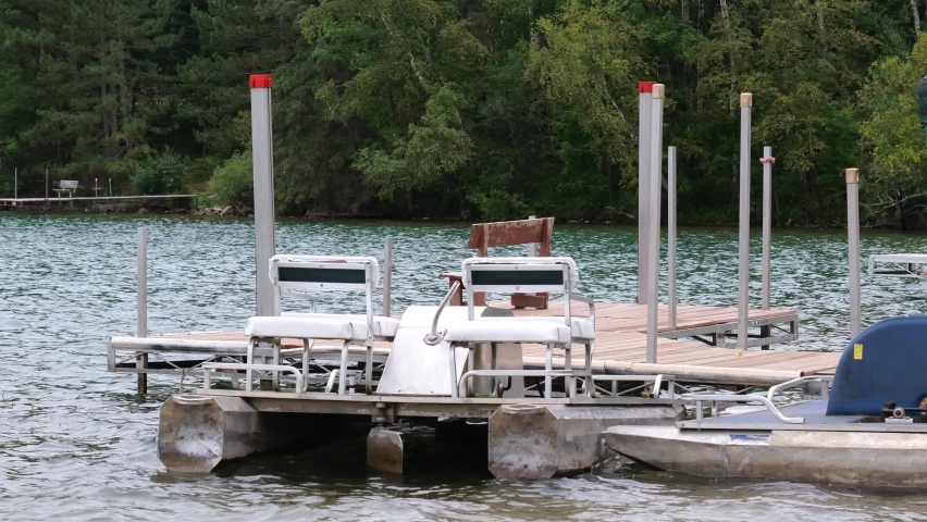 Paddle boats, moored at the dock, bobbing gently on the waves of a beautiful Minnesota lake, as they float on the water.