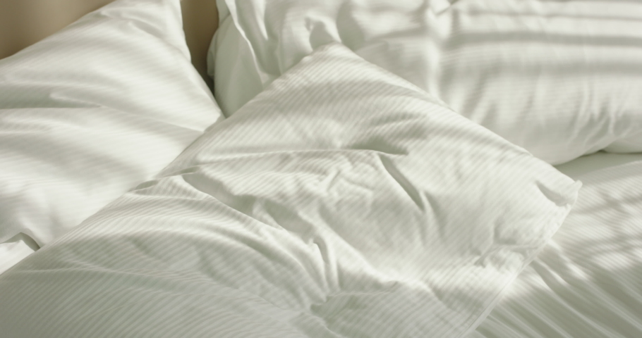 Young pretty asian girl falling onto cozy comfortable bed, happily smiling and relaxing early in morning. Sensual gen z girl enjoying weekend morning 4k footage