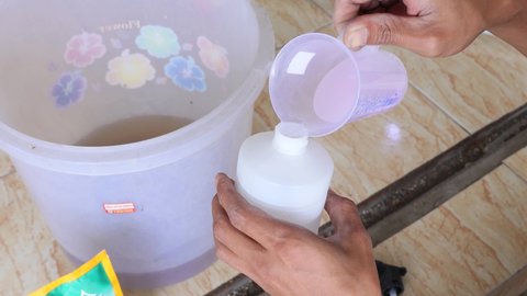 Jakarta Indonesia - September 10 2021 : prepare and mix simple chemical cleaner liquid detergent and perfume for washing and cleaning floor surface and carpet using plastic can and bottle before used
