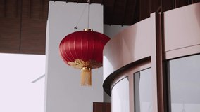One large fringed red Chinese lantern adorns entrance to the modern building, close-up. Festive decor of houses in the city. The decoration sways in the wind. - Powered by Shutterstock - Get 15% off with code: PIKWIZARD15