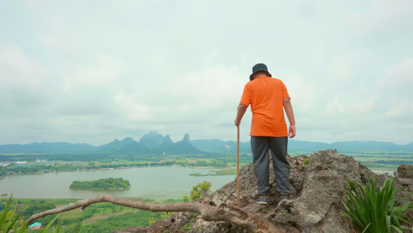  Fit Asian boy hiking up a mountain and enjoying the view on the island of Thailand, Enjoys the peace and quiet of the natural landscape with hills and trees in the background