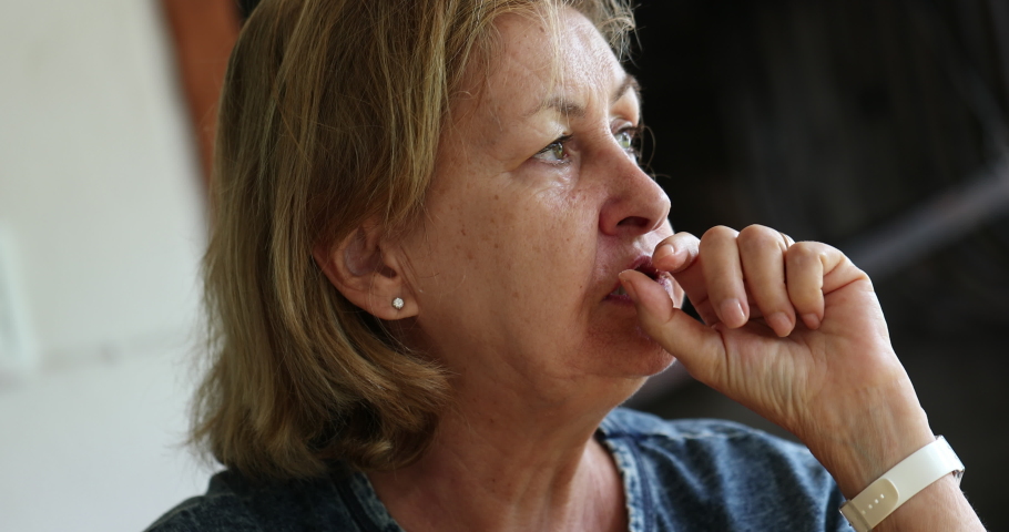 Pensive older woman thinking deeply while chewing. Thoughtful senior woman lost in thought