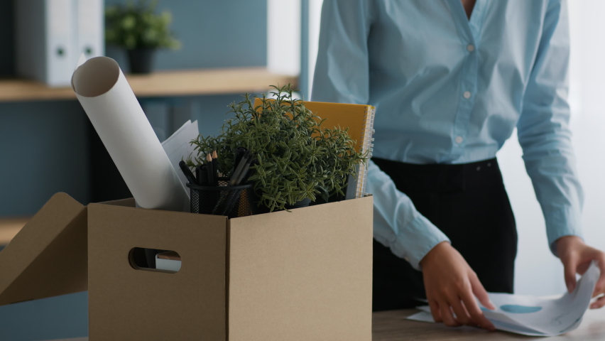 Dismissal And Resignation. Unrecognizable Fired Female Office Worker Packing Stuff In Cardboard Box Leaving Workplace Quitting Job Standing Indoors. Employment Of Employees Concept. Cropped Royalty-Free Stock Footage #1079107712