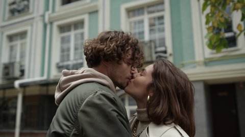 Portrait of love couple kissing on city street. Affectionate man circling woman in arms outdoor in slow motion. Young lovers feeling happy during romantic date on urban background. Video stock