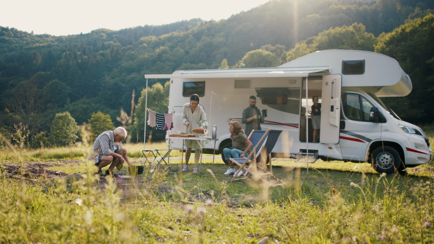 Multi-generation family preparing dinner outdoors by car, caravan holiday trip. | Shutterstock HD Video #1079115011