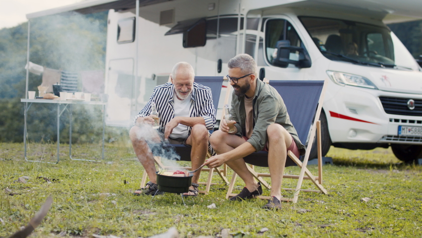 Mature man with senior father talking at campsite outdoors, barbecue on caravan holiday trip. Royalty-Free Stock Footage #1079115017