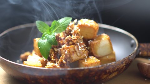Stir Fried Tofu hot with sesame seeds in a pan. Homemade healthy vegan asian meal - fried tofu.