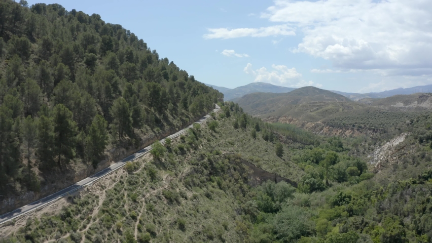 Striking green mountainous terrain with a road running through and blue sky.