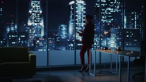 Successful Caucasian Businesswoman Wearing Stylish Suit Holding Laptop Standing in Big City Night Office. Female CEO Managing Environmental, Social and Corporate Governance for e-Commerce Project