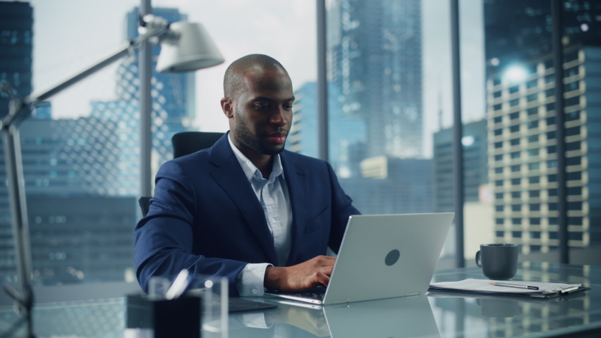 Successful Black Businessman in Tailored Suit Working on Laptop Computer on Top Floor Office Overlooking Big City. Professional CEO Managing Environmental, Social and Corporate Governance | Shutterstock HD Video #1079127443