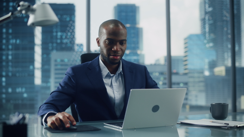 Successful Black Businessman in Tailored Suit Working on Laptop Computer on Top Floor Office Overlooking Big City. Professional CEO Managing Environmental, Social and Corporate Governance Royalty-Free Stock Footage #1079127443