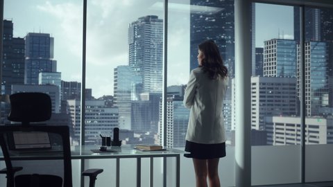 Ambitious Successful Businesswoman Standing in Office Looking out of Window on Big City. Confident High Achievement Female Digital Entrepreneur Thinking of Investment Strategy for e-Commerce Software