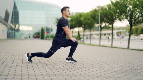 young active asian fit man engaged in physical exercise stretching outdoor street. Male athlete in sportswear workout urban city park. Healthy Lifestyle Sports fitness outside. Warm-up before jogging