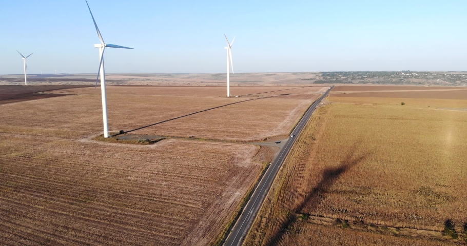 Car Traveling On Country Road Passing By Wind Turbines On Sunset. Aerial Drone Royalty-Free Stock Footage #1079130272