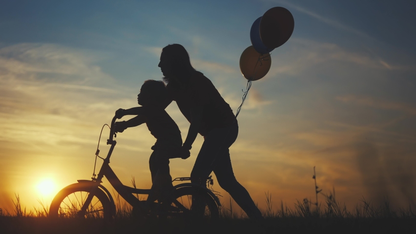 Mom teaches son to ride a bike. happy family kid dream concept. mom and child son learn to ride a bike silhouette in the park in nature. happy family doing sports outdoors sunlight in the park . | Shutterstock HD Video #1079133902