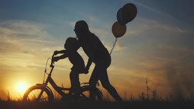 mom teaches son to ride a bike. happy family kid dream concept. mom and child son learn to ride a bike silhouette in the park in nature. happy family doing sports outdoors sunlight in the park . - Powered by Shutterstock - Get 15% off with code: PIKWIZARD15