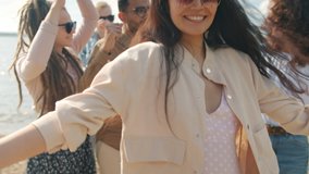 Joyful Asian woman is dancing on beach with friends multi-ethnic group having fun on summer day smiling and looking at camera. Youth and lifestyle concept. - Powered by Shutterstock - Get 15% off with code: PIKWIZARD15