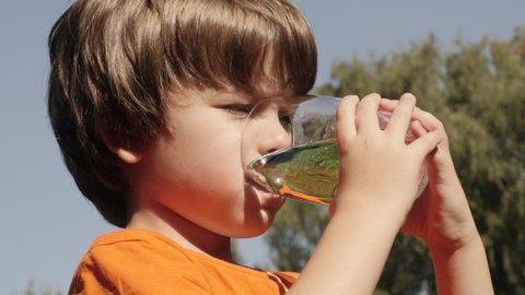 Thirsty Child Drinking Water From Glass Outdoors With Sun Shining. Kid Boy Drinking Glass Fresh Transparent Pure Filtered Water Slow Motion Kid Drinking Cup Water Healthy Body Care Healthy lifestyle