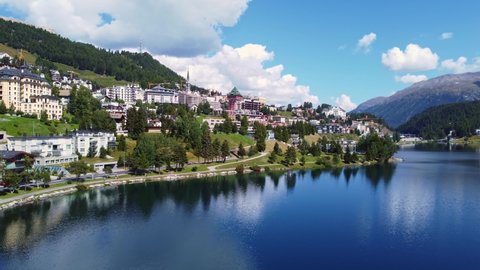 Aerial drone footage of Saint Moritz ski resort and lake on a sunny summer day in the Graubunden canton in the alps in Switzerland. Shot with a forward and tilt down motion. 