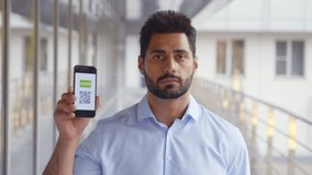 Medium shot of indian young man showing qr-code and covid19 passport on cellphone. Portrait of smiling male looking at camera holding electronic vaccination certificate on smartphone - Powered by Shutterstock - Get 15% off with code: PIKWIZARD15