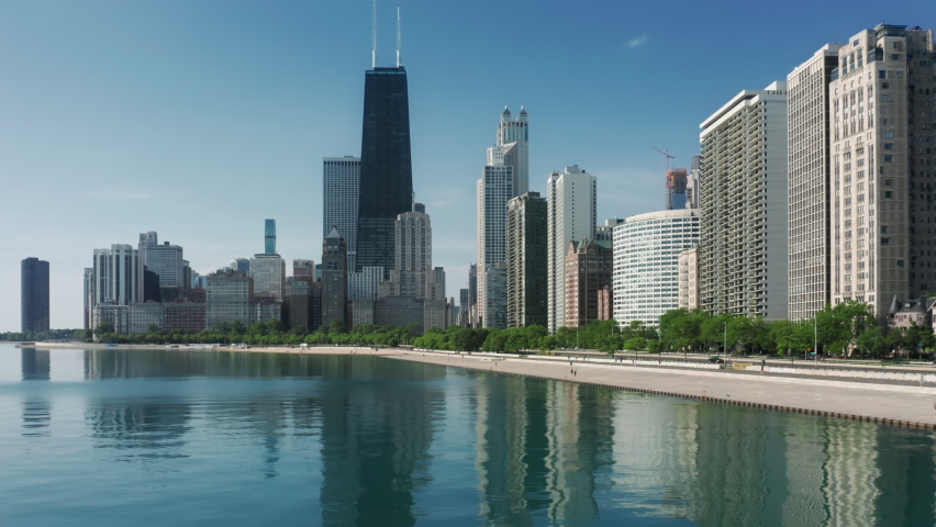 Cinematic modern city coastline on a sunny summer day. Aerial shot of the prestige residential apartments at the Michigan lake bay. 4K beautiful cityscape, Chicago Illinois, United States of America